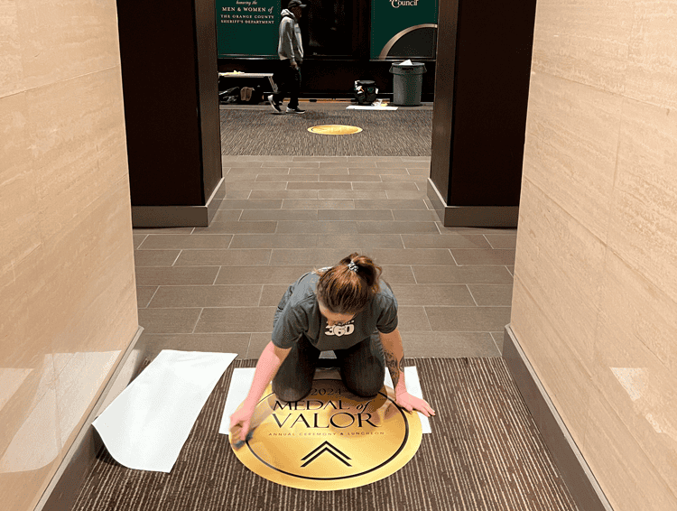 a person is installed a floor graphic decal onto carpet in a hotel