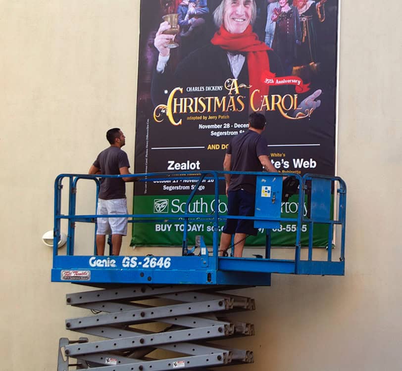 2 people installing a banner using a scissor lift